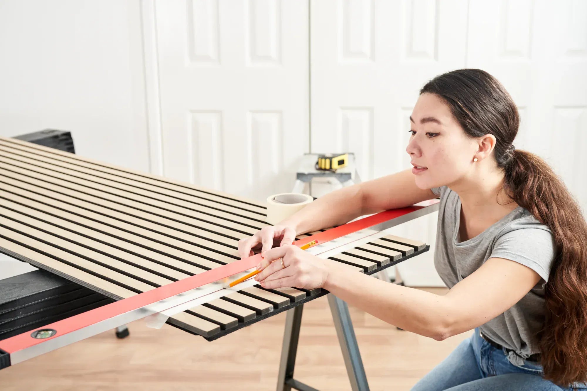 woman marking cutting line for trimming of wood slat wall panels