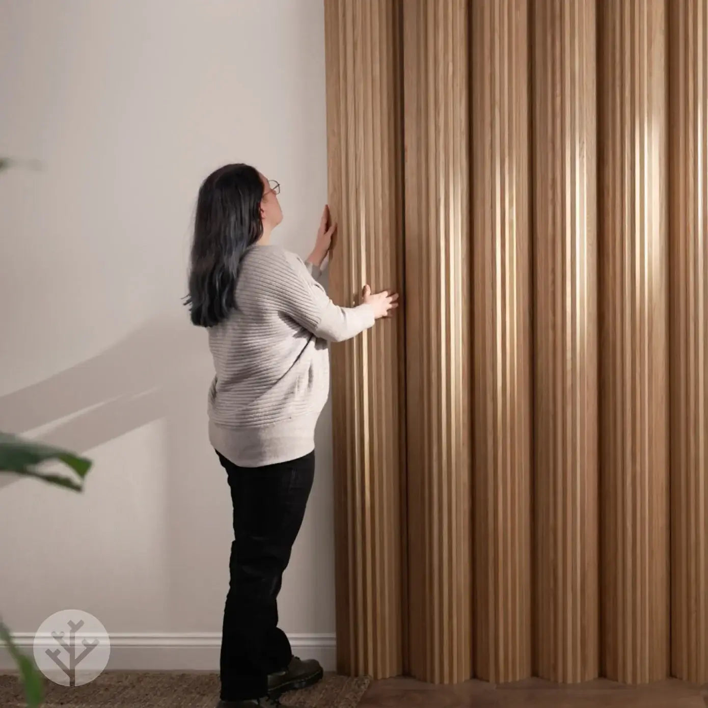 Person installing Flutto™ Oak Zigzag flexible wood panels in a modern interior setting.