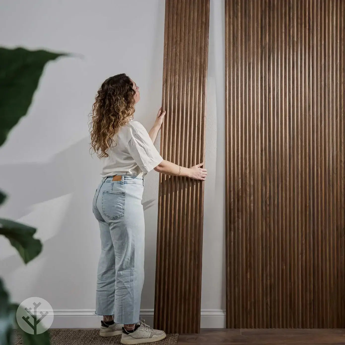 Person installing Flutto™ Walnut Zigzag flexible wood panels in a modern interior setting.