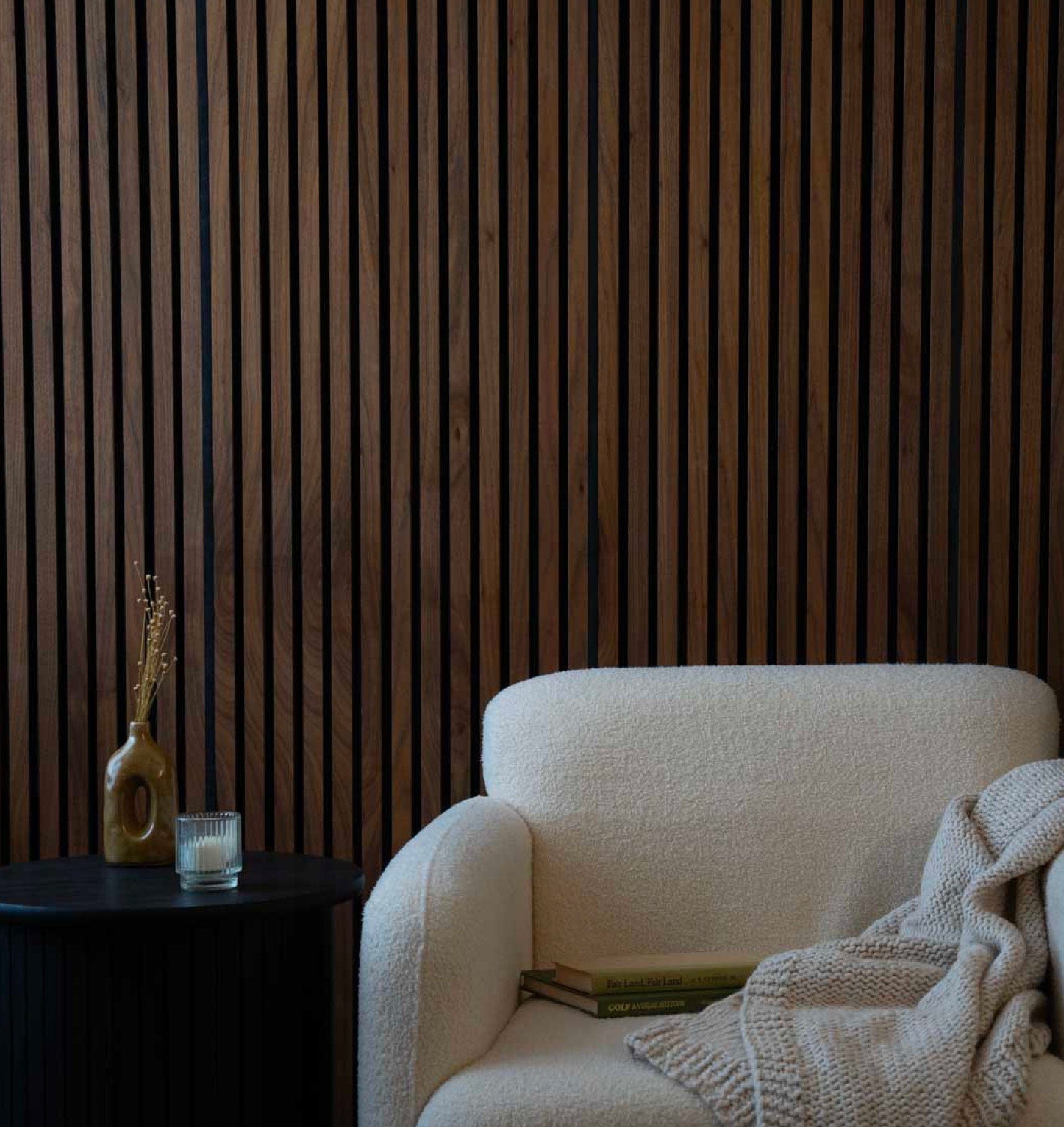 White armchair with a blanket against a wooden paneled wall.