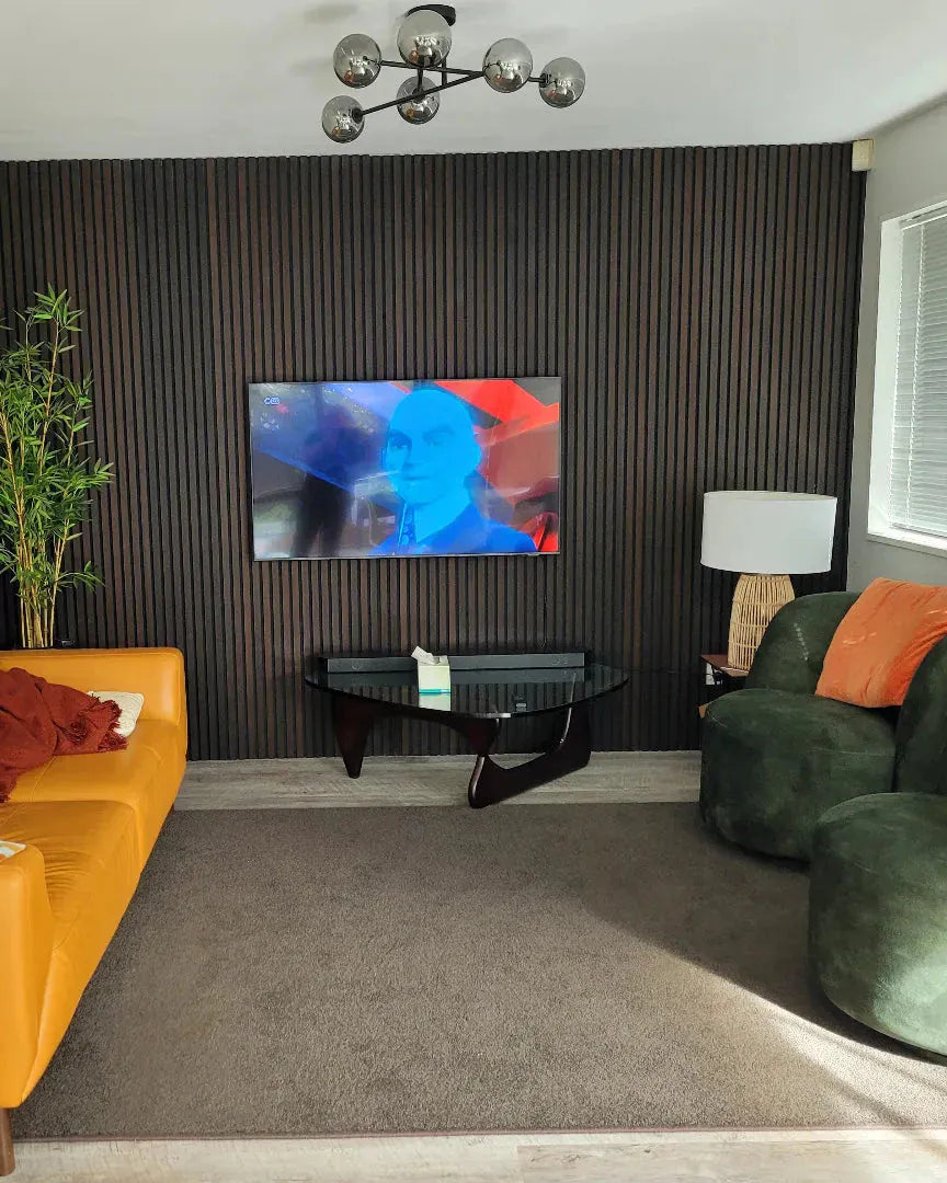 Living room with orange sofa, green armchair, and abstract painting on wall.